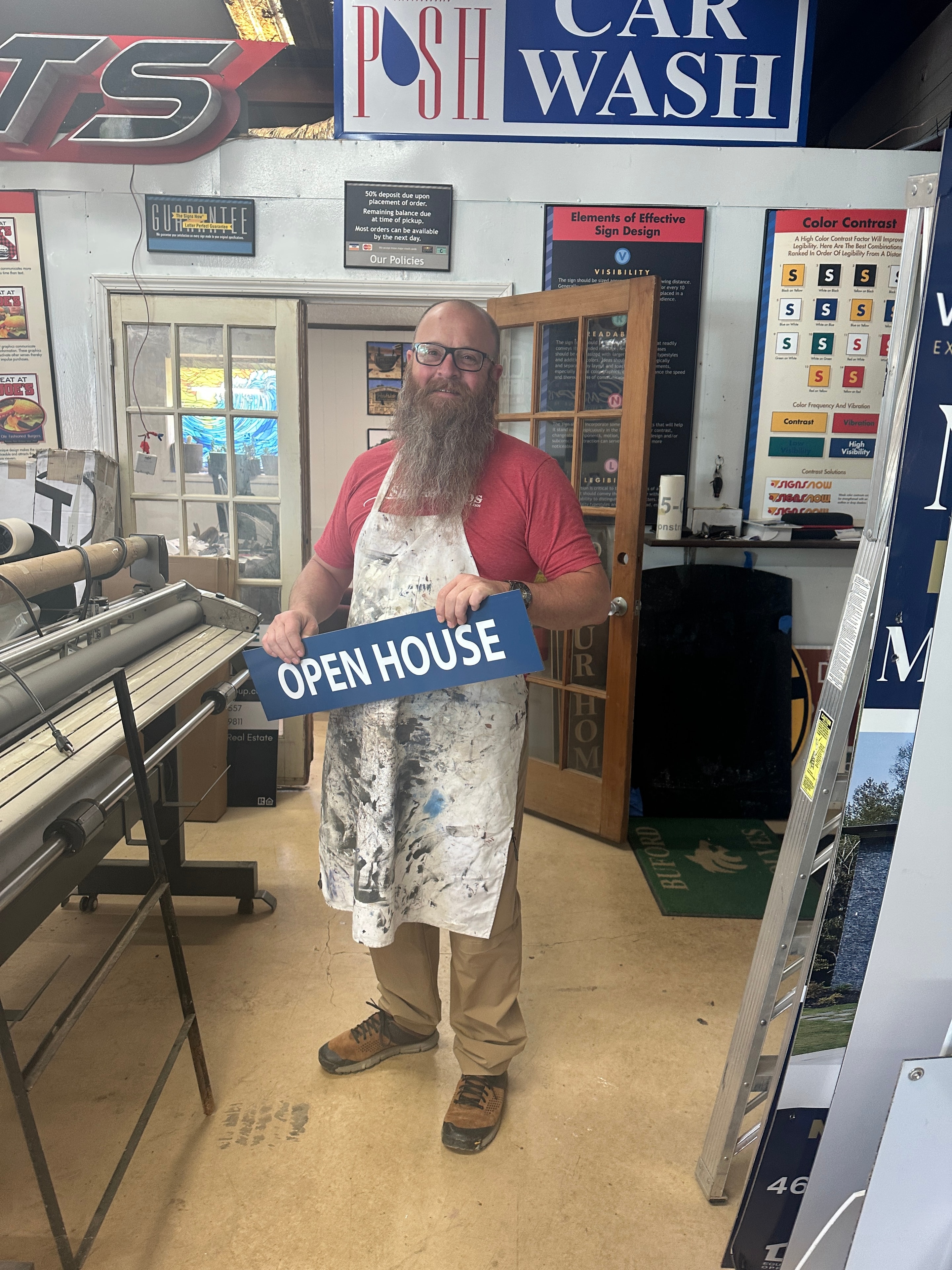 SignsandWraps craftsman holding a custom Open House sign in the shop