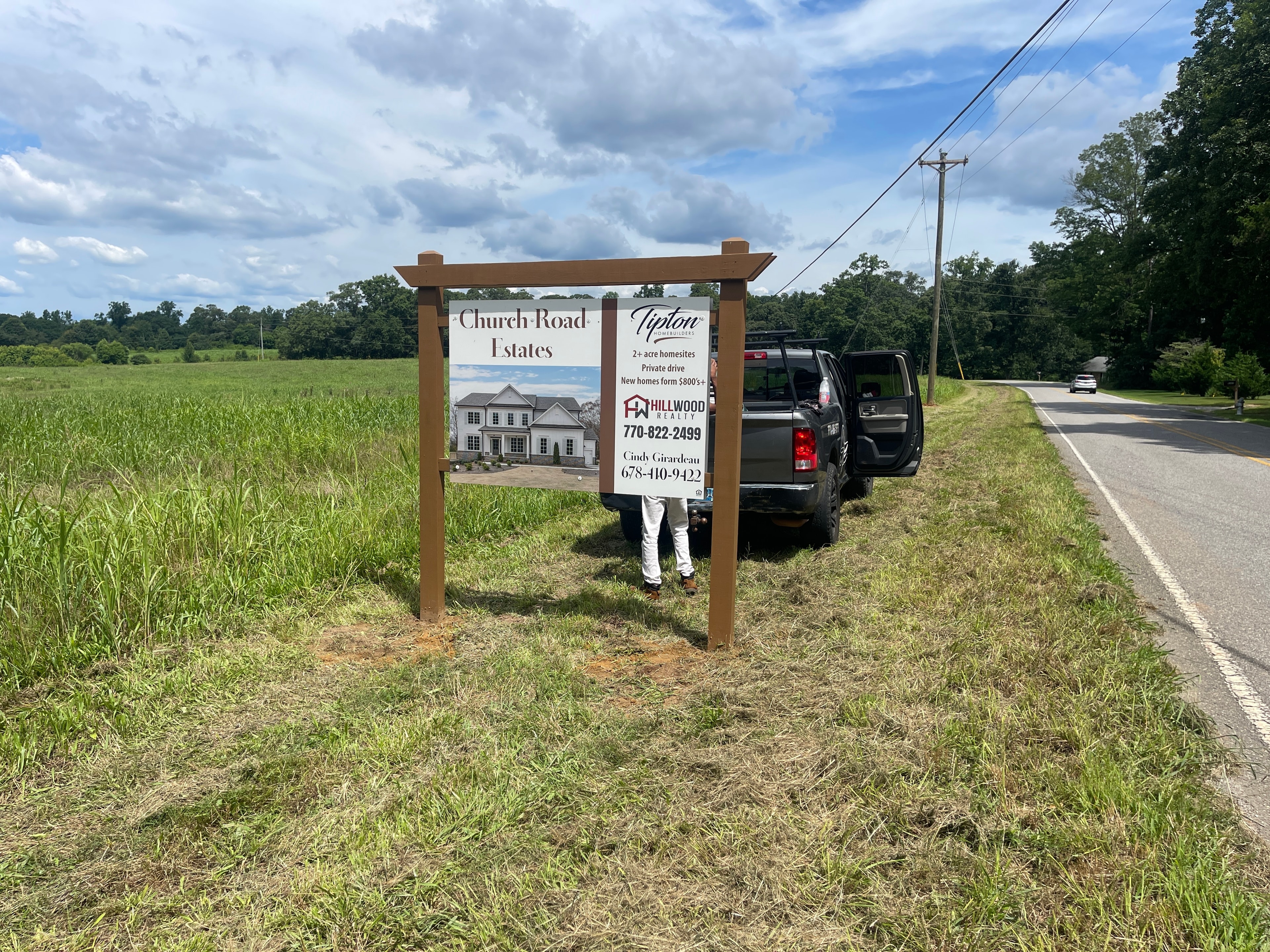 Church Road Estates Tipton Homes roadside sign with Hillwood Realty branding on wooden post frame