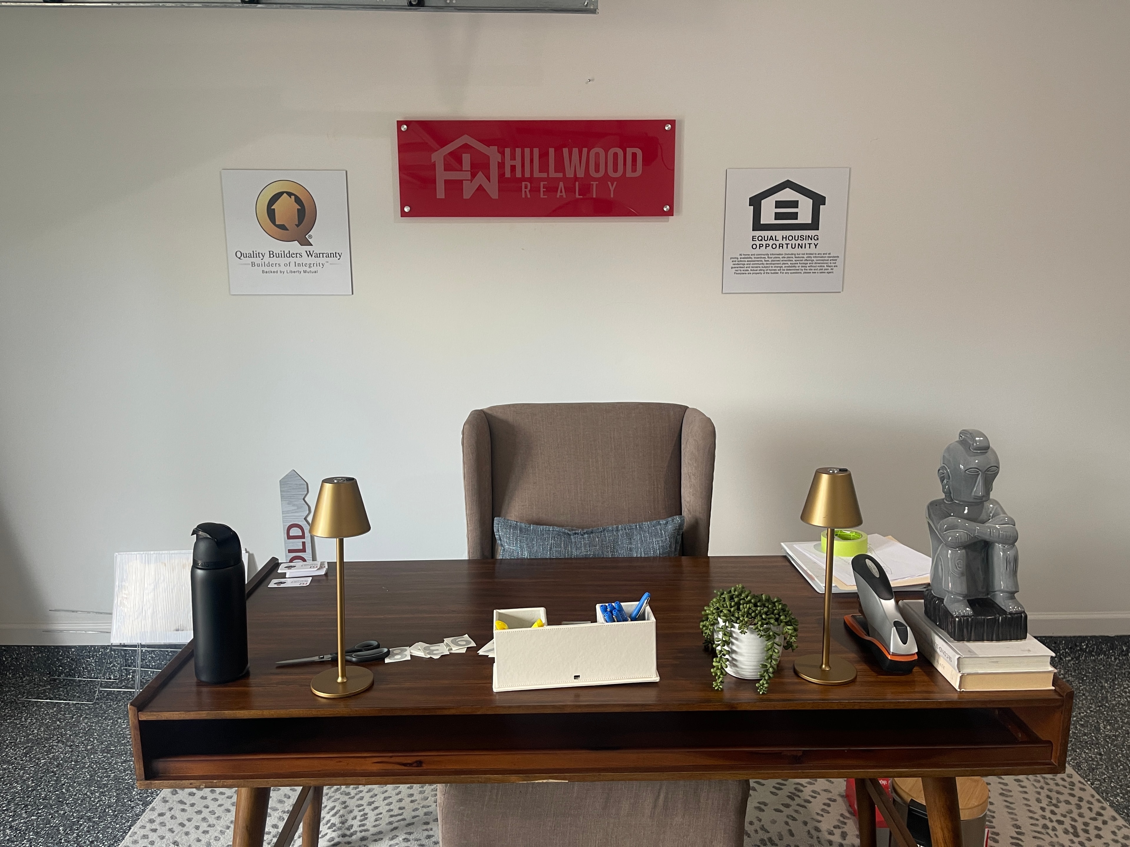 Hillwood Realty acrylic wall sign with Quality Builders Warranty and Equal Housing Opportunity signs in real estate office