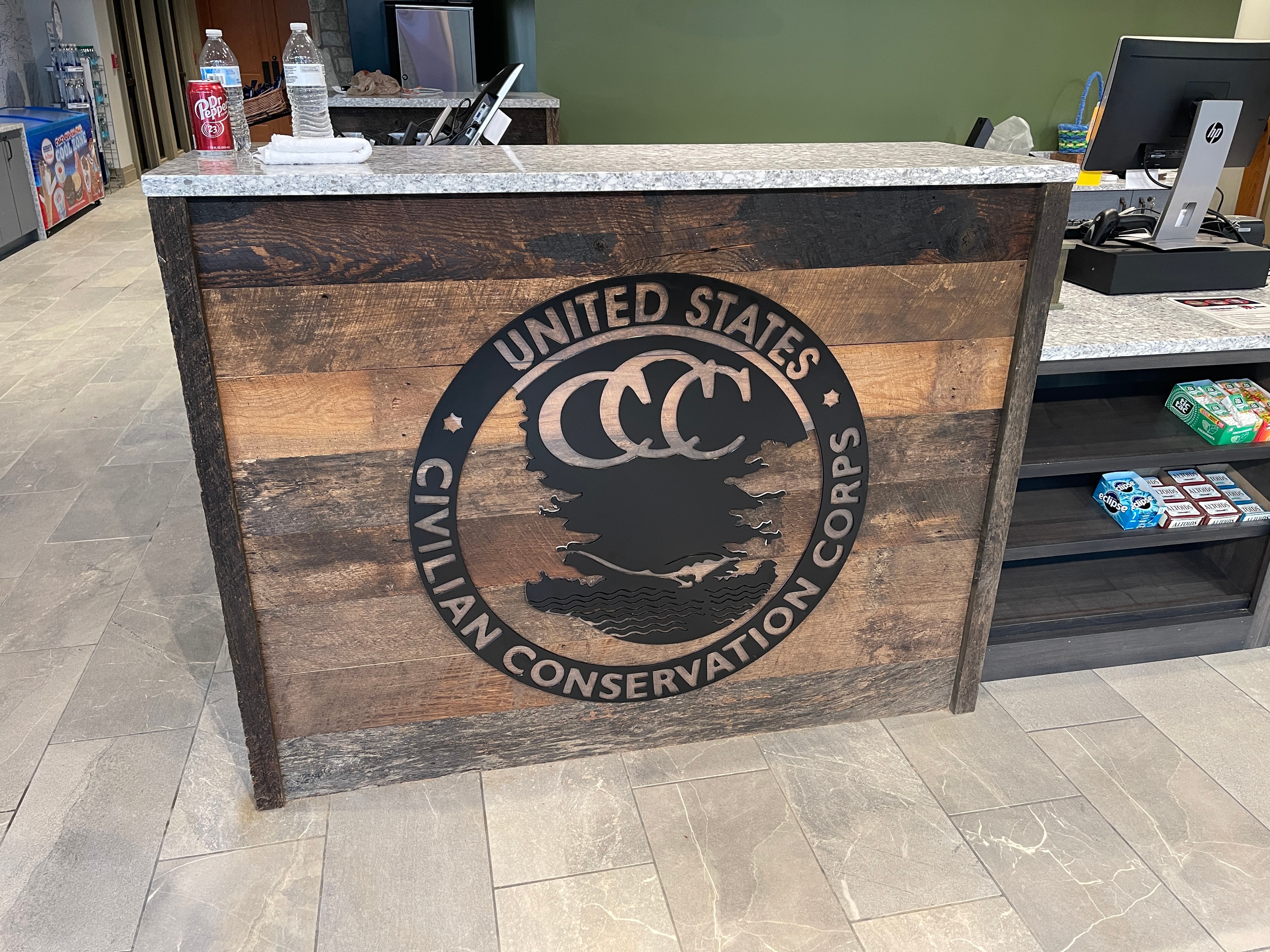 Custom CCC Civilian Conservation Corps medallion sign on reclaimed wood reception desk at Vogel State Park Visitor Center